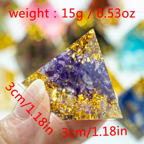 Triangular crystal with purple and gold colors, held by a hand, with measurements and weight displayed.
