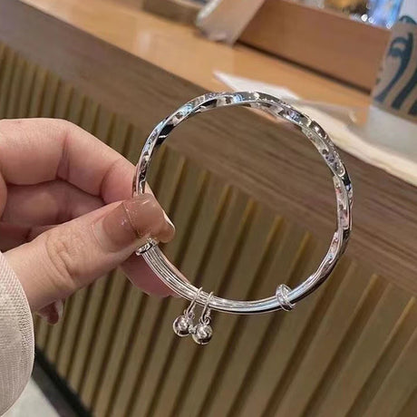 Silver bracelet held by a hand with a blurred background