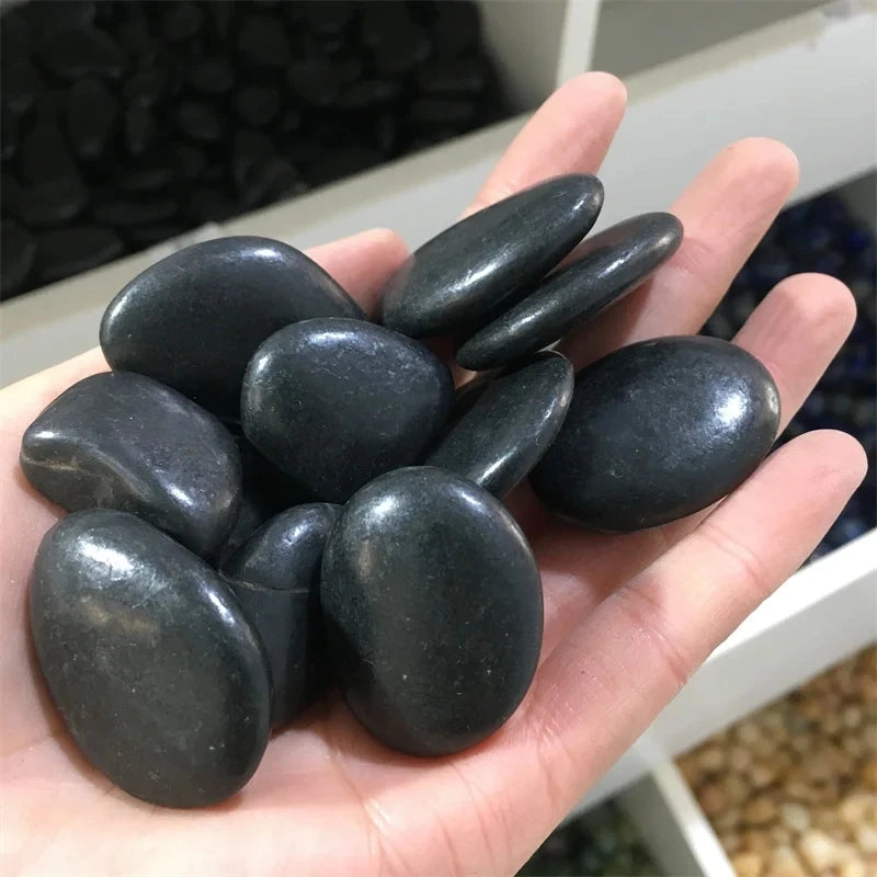 Hand holding a handful of dark stones with a blurred background