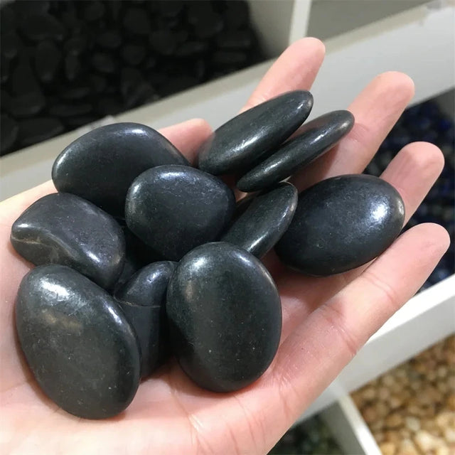 Hand holding a handful of dark stones with a blurred background