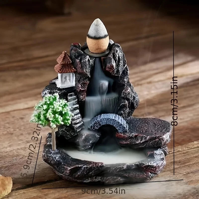 Decorative incense burner with mountain and temple design on a wooden surface