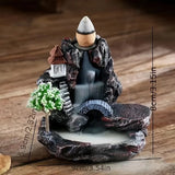 Decorative incense burner with mountain and temple design on a wooden surface