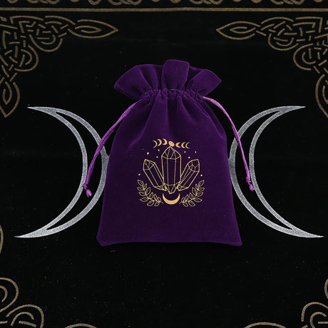 Purple drawstring bag with crystal design on a black background with moon symbols