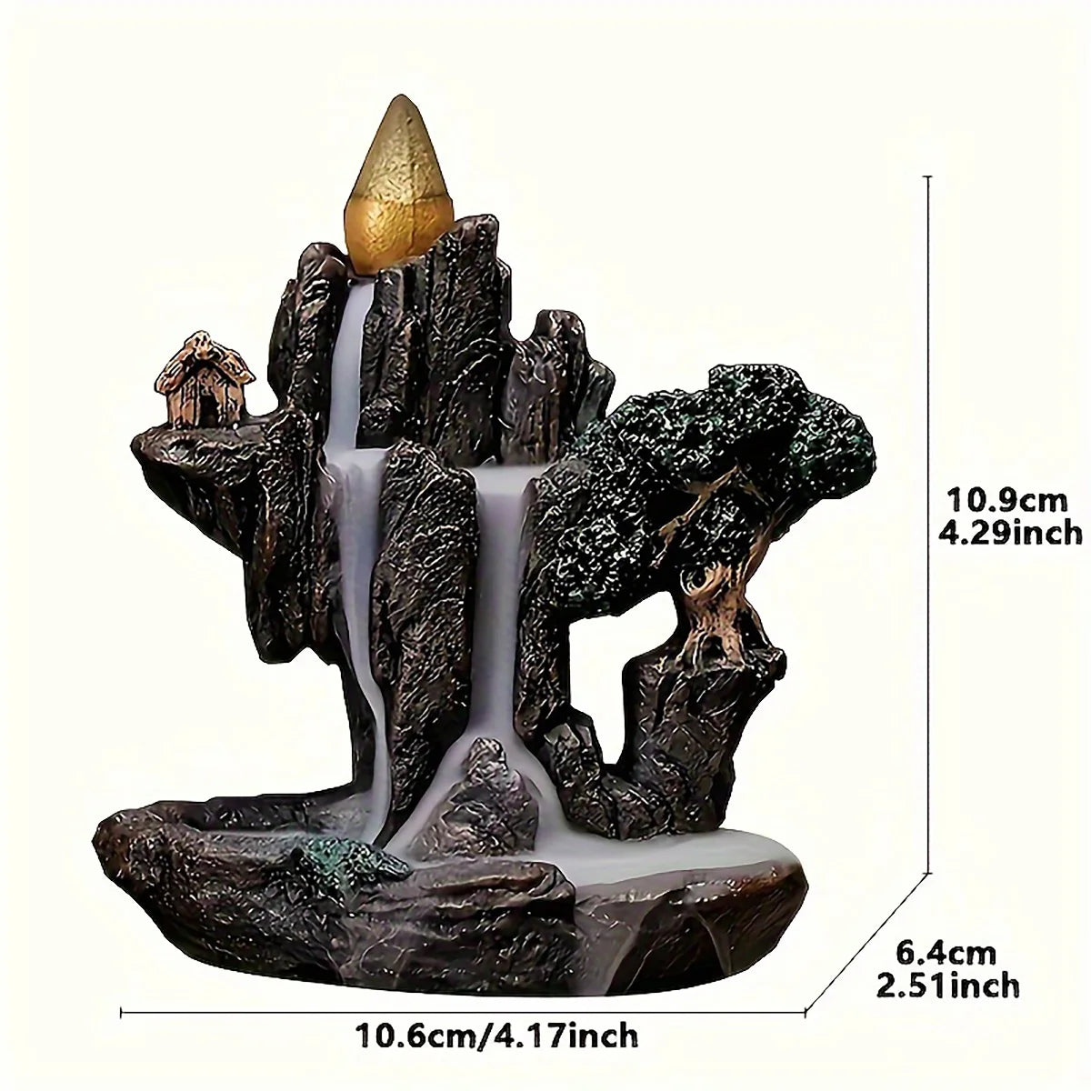Decorative backflow incense burner with a mountain and house design, featuring a small golden cone on top.