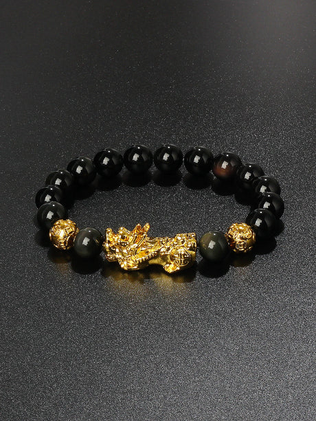 Black beaded bracelet with gold accents on a dark surface
