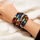 Multicolored beaded bracelets on a wrist against a white fabric background