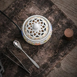 Decorative ceramic incense burner with intricate design on a textured surface