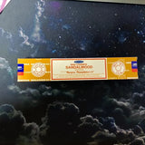 Box of Satya Sandalwood incense on a dark background with smoke effect