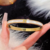 Gold bracelet with white stones held by a hand on a fluffy black surface
