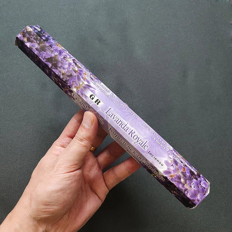 Hand holding a package of Lavanda Royale incense sticks against a dark background