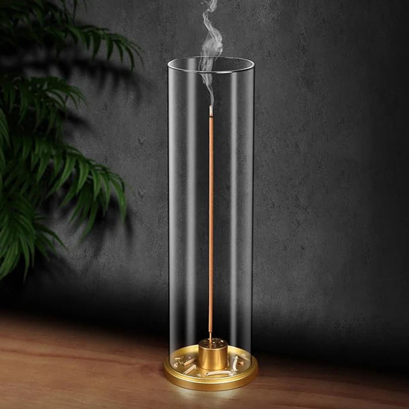 Clear cylindrical incense burner with a lit incense stick on a dark background