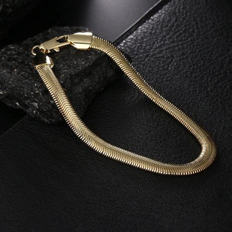 Gold snake chain bracelet on a dark textured surface