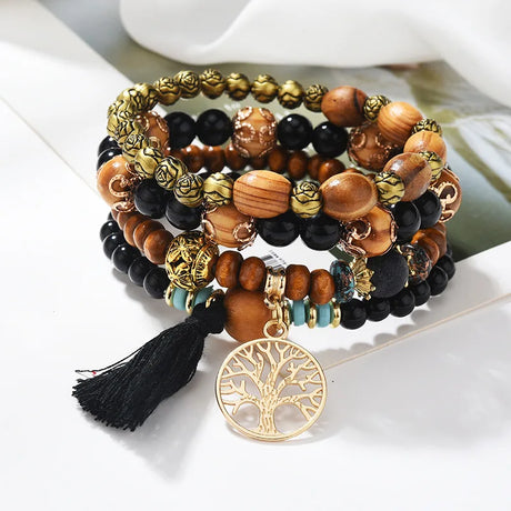 Stack of beaded bracelets with a prominent tree of life charm on a white surface.