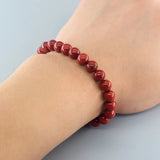 Red beaded bracelet on a wrist against a light gray background