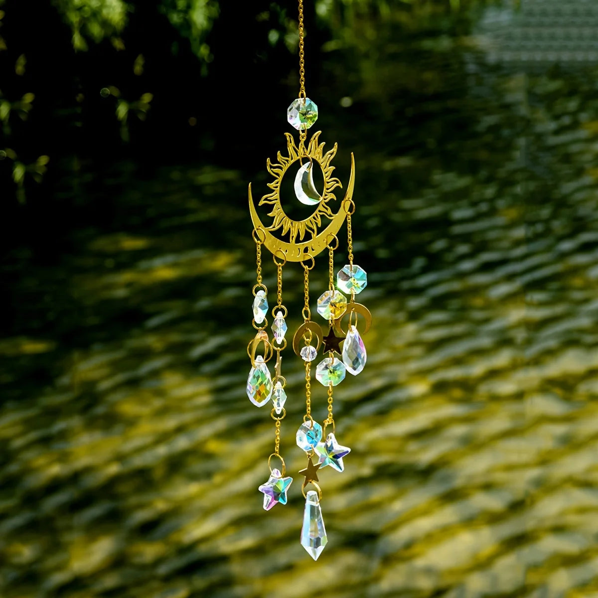 Decorative hanging ornament with crystals and celestial design against a green foliage background