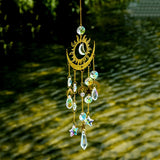 Decorative hanging ornament with crystals and celestial design against a green foliage background