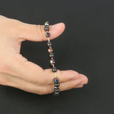 Hand holding a beaded bracelet against a black background