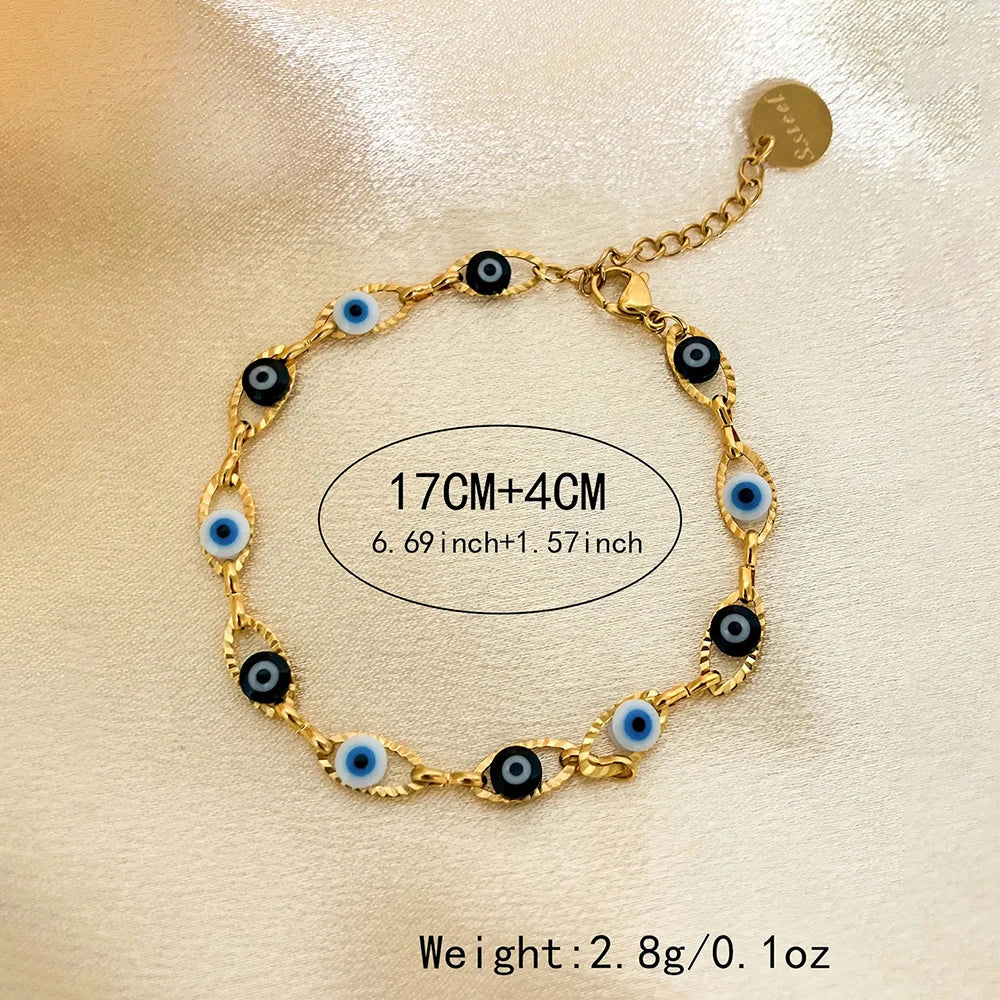 Gold bracelet with black and blue evil eye charms on a beige background