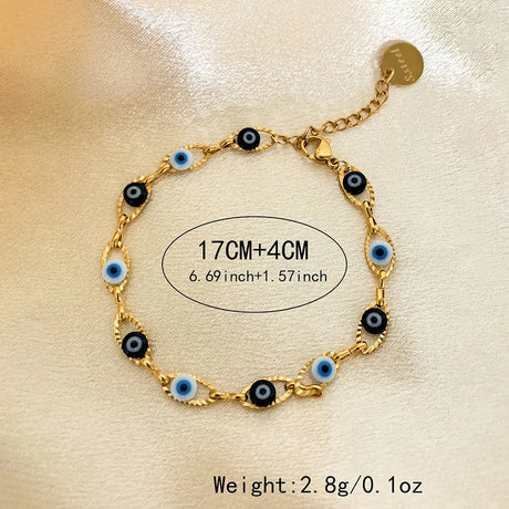 Gold bracelet with black and blue evil eye charms on a beige background