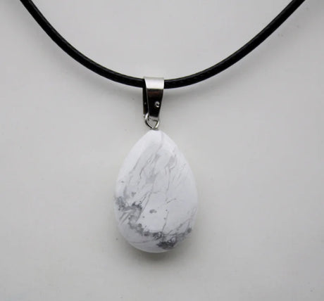 Teardrop-shaped marble pendant on a black cord against a light gray background