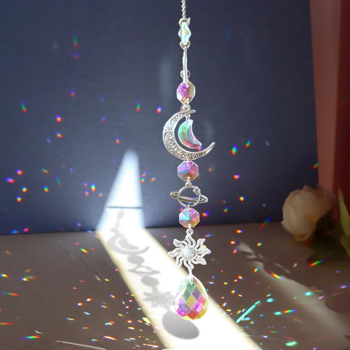 Decorative hanging ornament with moon and sun design on a dark background with rainbow