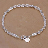 Silver rope chain bracelet with a heart charm on a beige background