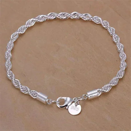 Silver rope chain bracelet with a heart charm on a beige background