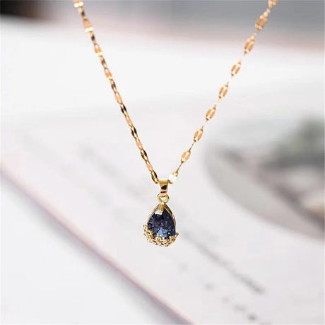 Gold necklace with a teardrop-shaped blue gemstone on a blurred background