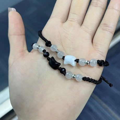 Hand wearing a bracelet with black, white, and gray beads on a blurred background
