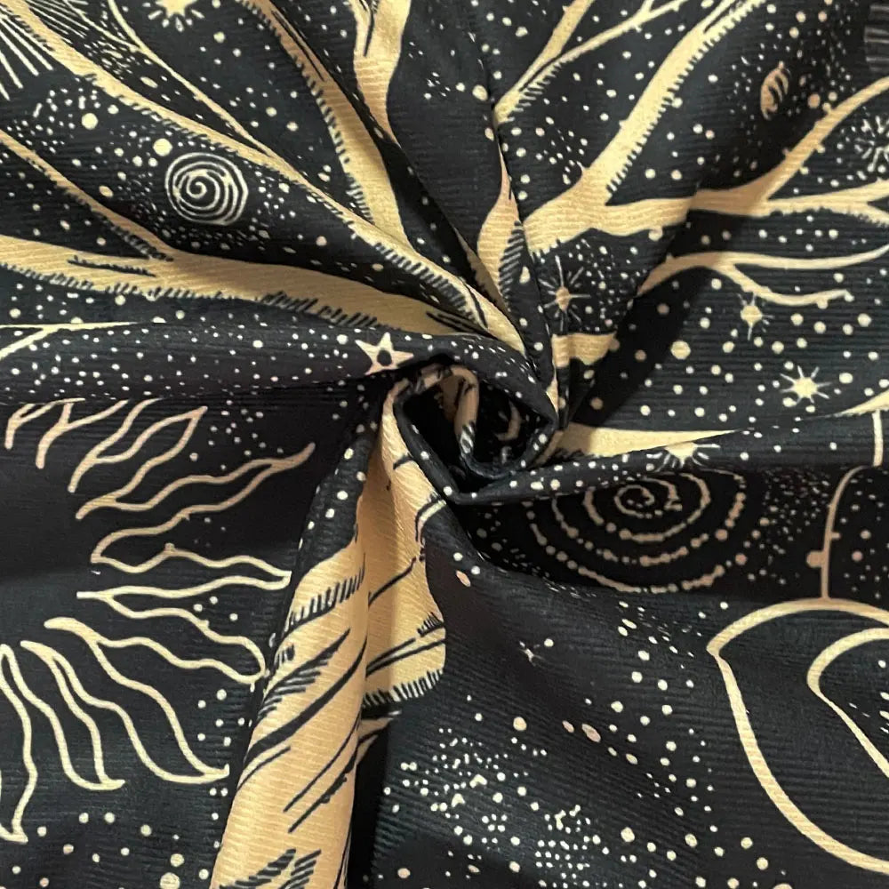 Fabric with celestial pattern featuring stars and cosmic designs on a black background