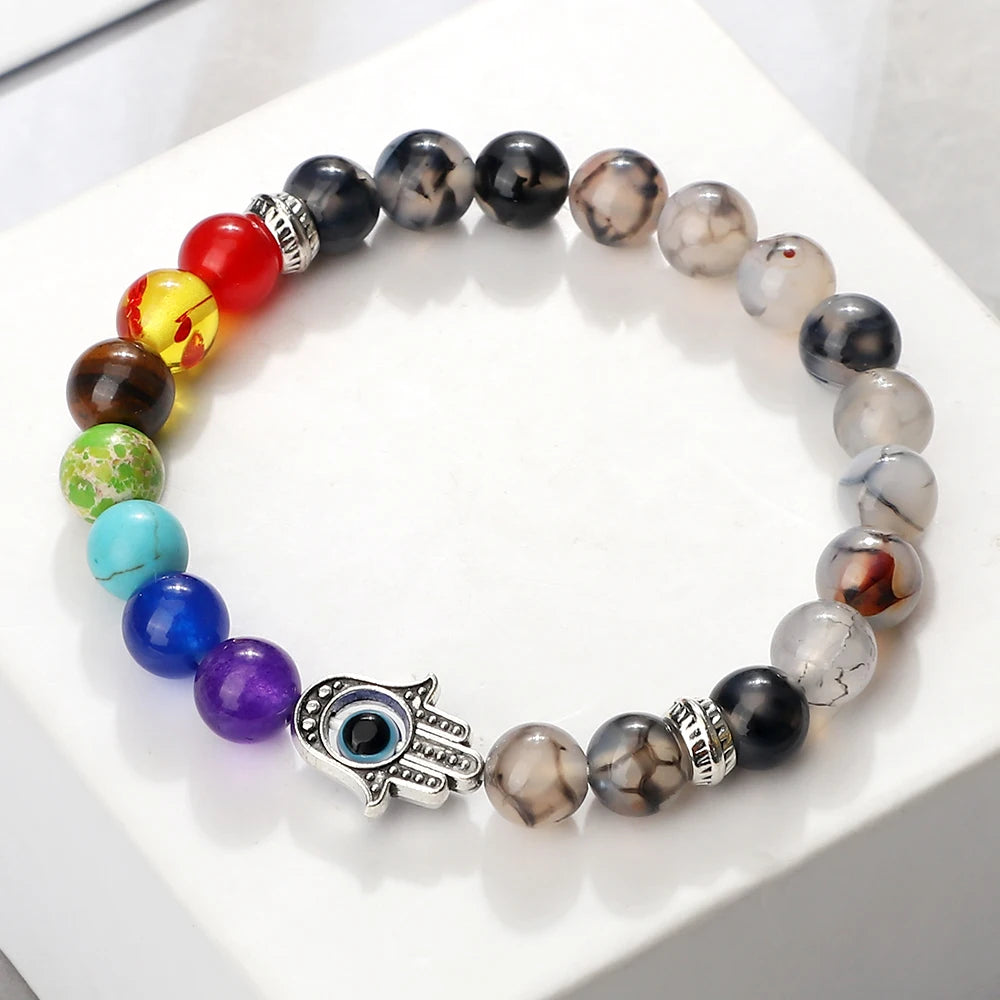 Multicolored beaded bracelet with a Hamsa hand charm on a white surface
