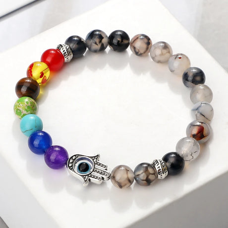 Multicolored beaded bracelet with a Hamsa hand charm on a white surface