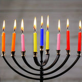 Black menorah with colorful candles against a gray background