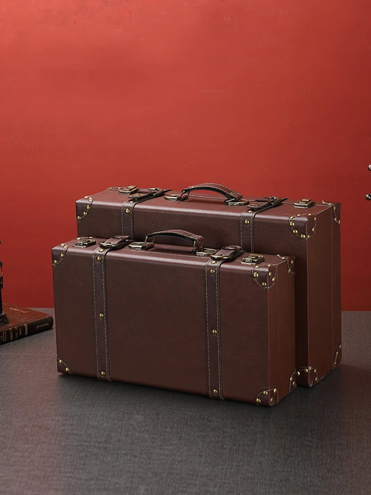 Two brown suitcases on a dark surface with a red background