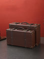 Two brown suitcases on a dark surface with a red background