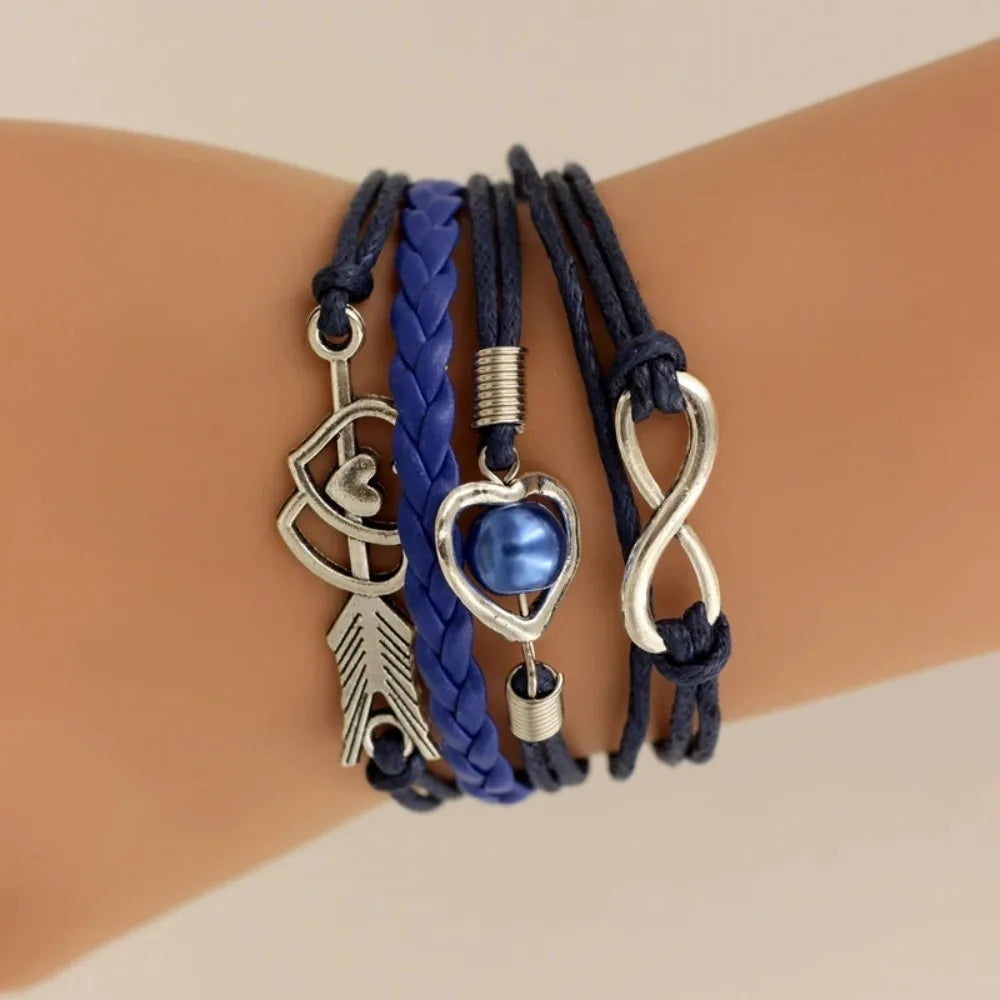 Three bracelets with various charms on a wrist against a beige background