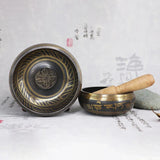 Tibetan singing bowl set with wooden striker on a textured surface