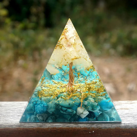 Triangular crystal with gold and blue elements on a wooden surface