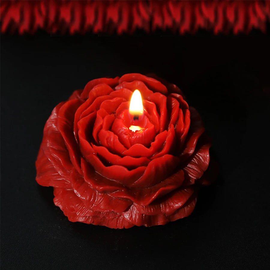 Red rose-shaped candle with a lit wick on a black background