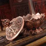 Copper incense burner with intricate designs on a wooden surface