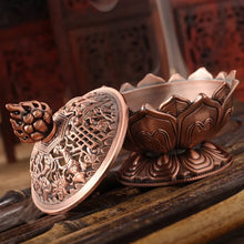 Copper incense burner with intricate designs on a wooden surface