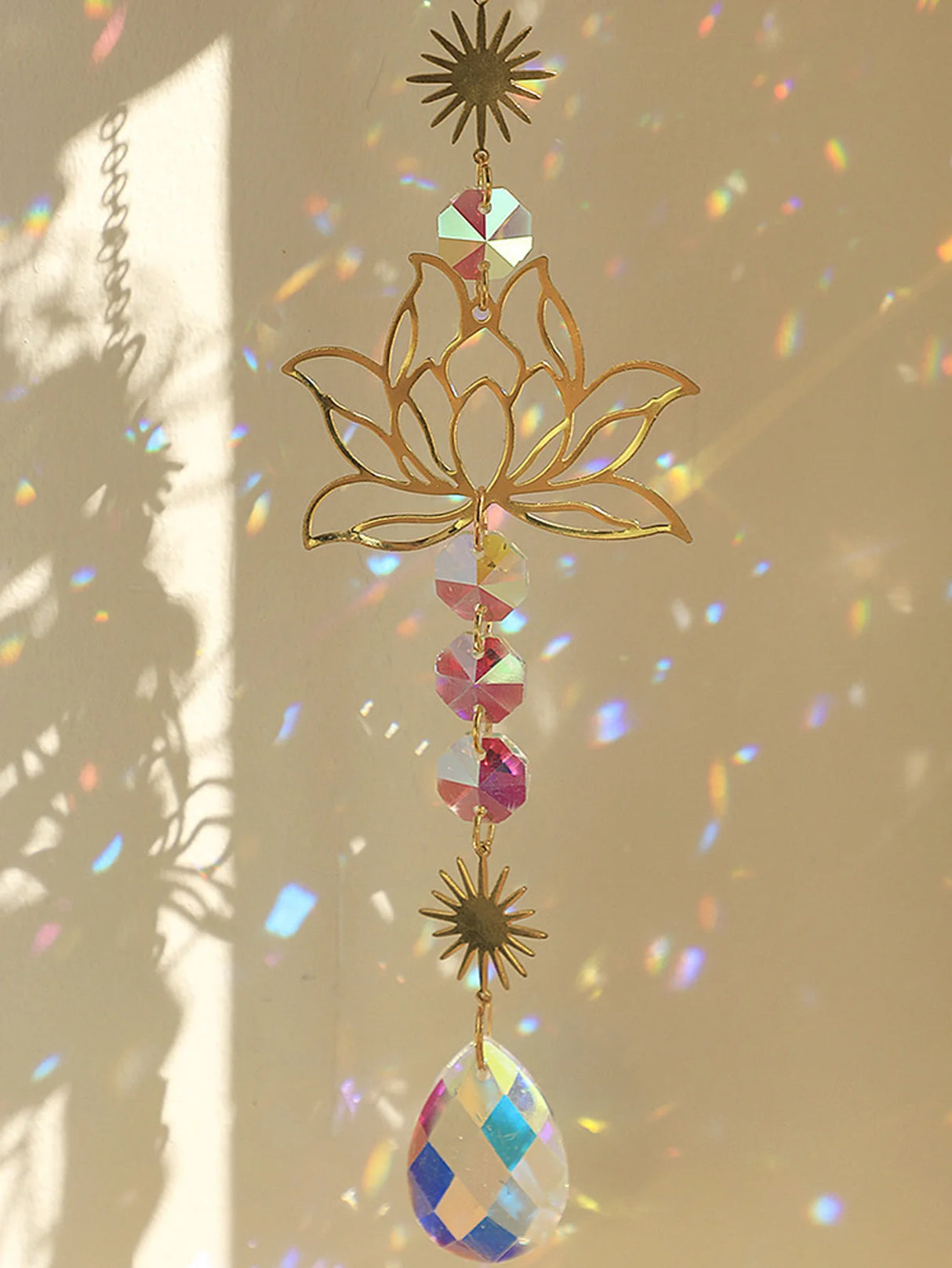Decorative hanging ornament with gold lotus design and colorful crystals on a beige background