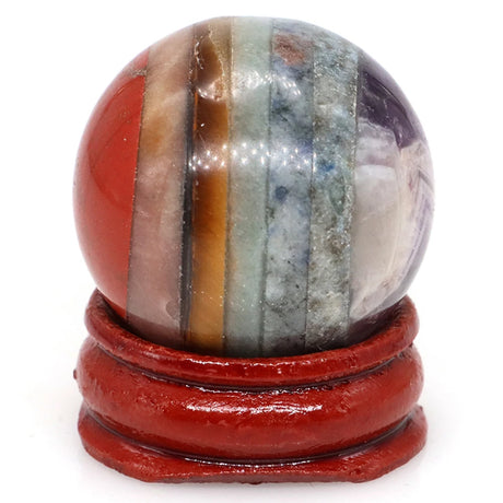 Multicolored striped stone sphere on a red stand against a white background