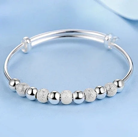 Silver bracelet with textured beads on a light blue background