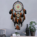 Dreamcatcher with feathers hanging on a gray wall with decor items below.