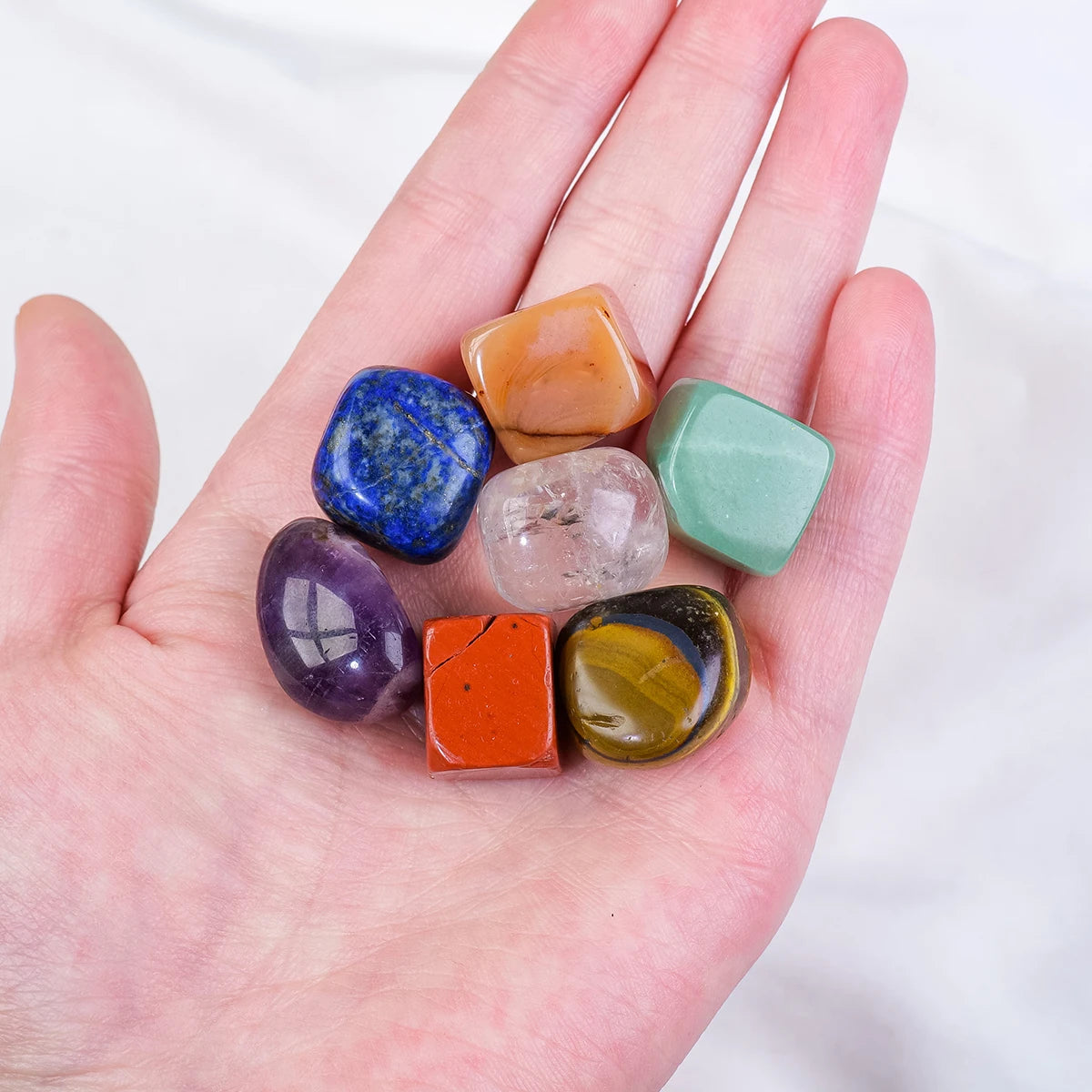 Hand holding a collection of colorful crystals on a white background