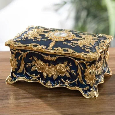 Decorative jewelry box with gold embellishments on a wooden surface