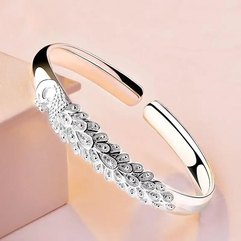 Silver bracelet with intricate design on a soft pink background