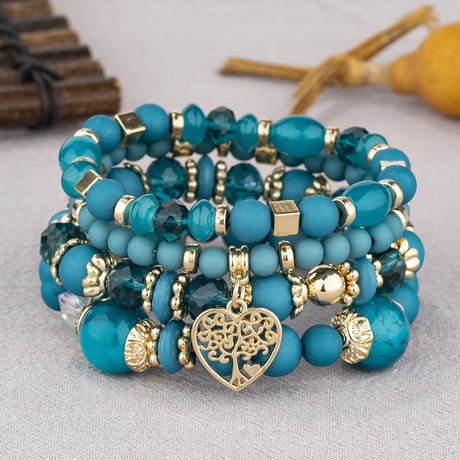 Stack of blue beaded bracelets with gold accents on a light gray background