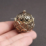 Decorative metal incense holder held in a hand against a dark background